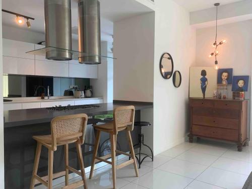 a kitchen with two chairs and a counter with a table at Malibu Langkawi Private Pool Villa in Pantai Cenang