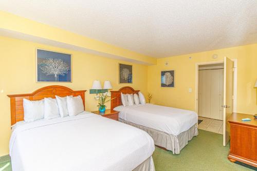 two beds in a hotel room with yellow walls at Spacious Oceanfront 2 Bedroom Suite - Sleeps 8! - Roxanne Towers Unit 406 in Myrtle Beach