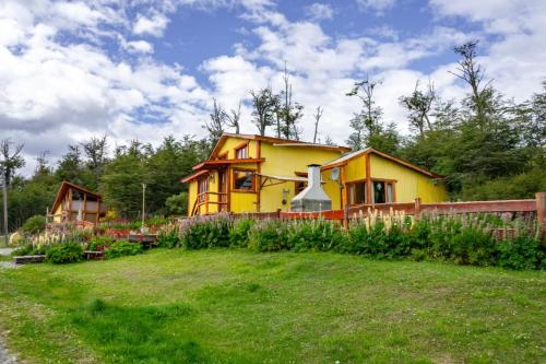a yellow house in the middle of a yard at Cabaña de las Flores in Tolhuin