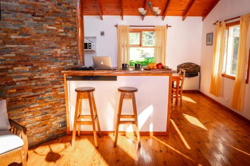 a kitchen with a counter and two bar stools at Cabaña de las Flores in Tolhuin