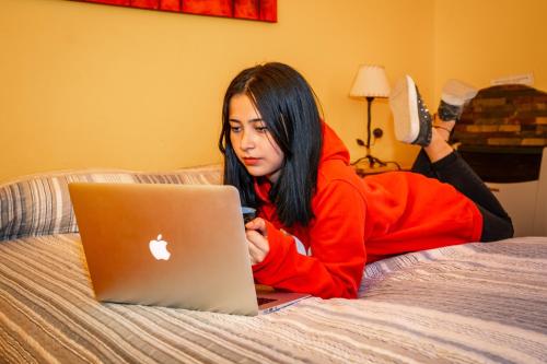 a woman laying on a bed with a laptop at Cabaña de las Flores in Tolhuin