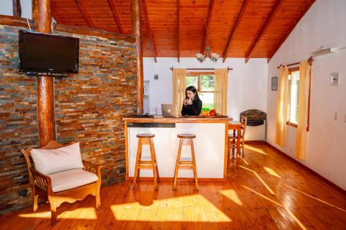 a woman sitting at a kitchen counter with a laptop at Cabaña de las Flores in Tolhuin