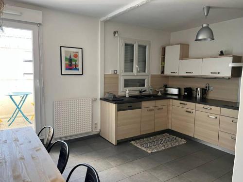 una cocina con armarios de madera y una mesa con sillas. en Superbe appartement avec parking en La Rochelle