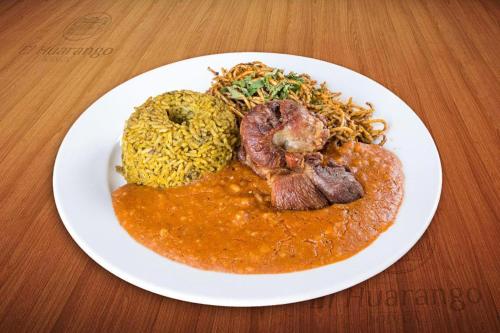 a plate of food with meat and rice on a table at Bodega el Huarango in Ica