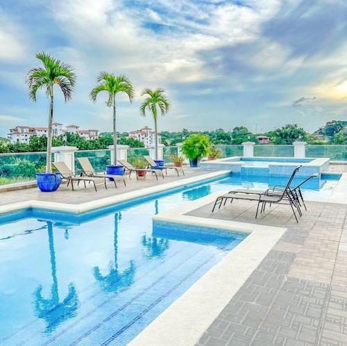 a swimming pool with chairs and palm trees on a building at Apa in San Carlos