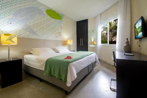 a bedroom with a bed with a green blanket at Armação dos Búzios Pousada Design in Búzios