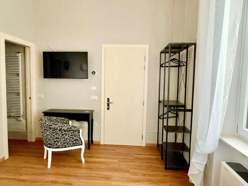 Habitación con silla, escritorio y TV. en Domus 44 Rooms en Verona