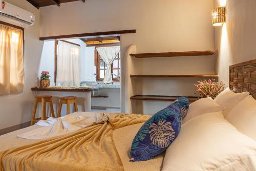 a bedroom with a bed and a kitchen with a counter at Chalé Chão de Trancoso Studios - Centro! in Trancoso