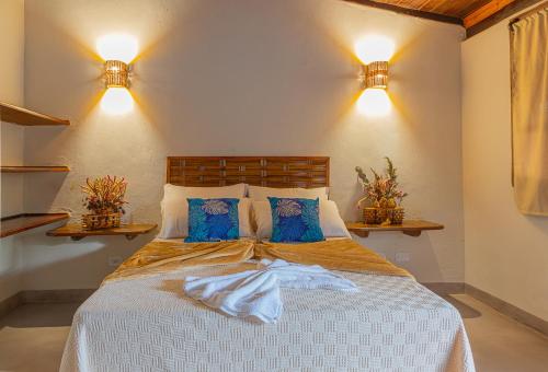 1 dormitorio con 1 cama con almohadas azules y 2 luces en Kalug - Chalé Chão de Trancoso Studios, en Trancoso