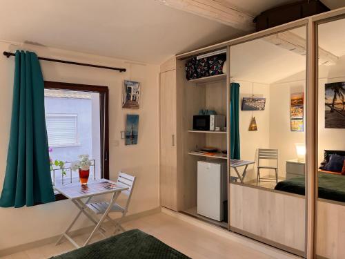 a small room with a table and a bedroom at Chambre cozy spacieuse, intra-muros, clim, parking in Aigues-Mortes