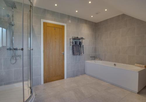 a bathroom with a tub and a glass shower at Breconview Lodge in Coelbren