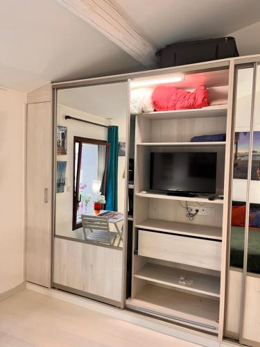 a room with a large glass enclosure with a tv in it at Chambre cozy spacieuse, intra-muros, clim, parking in Aigues-Mortes