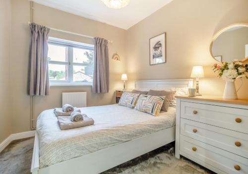 a bedroom with a bed with a dresser and a window at The Old Post Office in Bentley