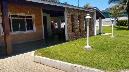 a brick house with a lamp in the grass at Casa para finais de semana temporada in Caraguatatuba