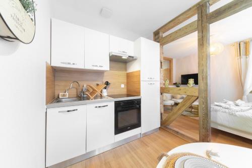 une petite cuisine avec des armoires blanches et un lit dans l'établissement Au Petit Lion, Colmar centre Garage gratuit, à Colmar