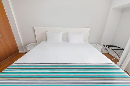 a bedroom with a white bed with a colorful striped rug at Capcana Hotel Jardins in Sao Paulo