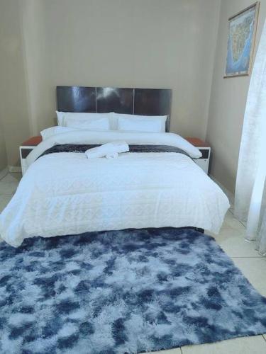 a bedroom with a large bed with a blue rug at ChoosersExpressHotel in Centurion