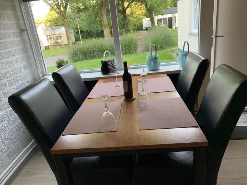 een houten tafel met een fles en glazen erop bij Vakantiehuis ontdek Zuid - Limburg in Simpelveld