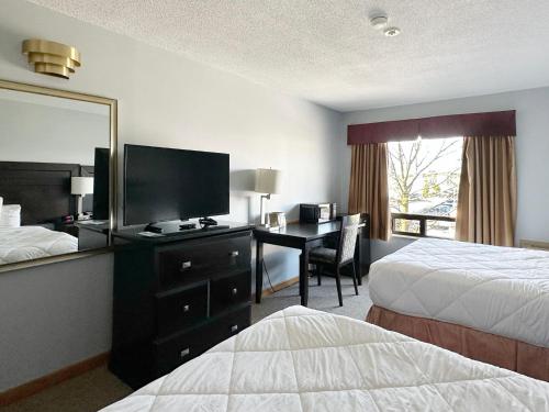 a hotel room with two beds and a desk with a television at Travelodge by Wyndham Welland in Welland