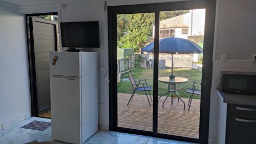 eine Küche mit einem Kühlschrank und einem Tisch mit einem Sonnenschirm in der Unterkunft Le refuge du voyageur in Sainte-Marie