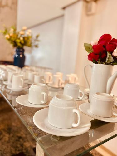 a group of cups and saucers on a table with roses at HOTEL CAMPO GRANDE in Campo Grande