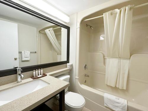 a bathroom with a sink and a toilet and a mirror at Travelodge by Wyndham Welland in Welland