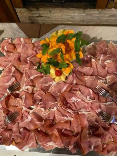 a plate of meat with forks and flowers on it at Lo Scoiattolo Country House in Montorio al Vomano
