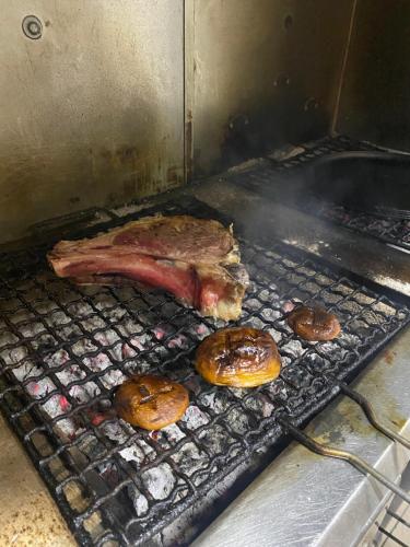 a piece of meat cooking on a grill with donuts at Lo Scoiattolo Country House in Montorio al Vomano