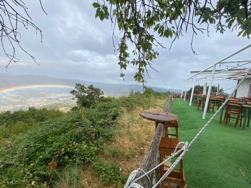 a table and chairs on a hill with a rainbow at Lo Scoiattolo Country House in Montorio al Vomano