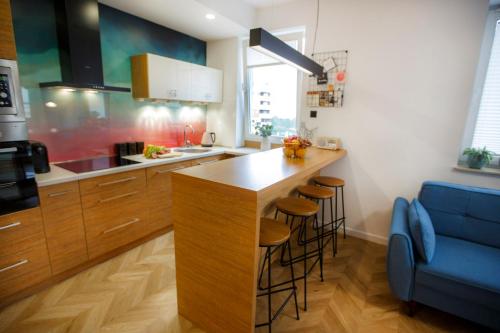 a kitchen with a bar with stools and a blue couch at Bochenka Apartments in Kraków