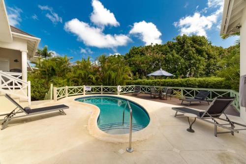 a swimming pool in a villa with chairs and a patio at Hullabaloo in Saint James