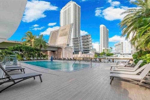 a swimming pool with chaise lounge chairs and buildings at Miami Studio 2 Full Beds in Hallandale Beach