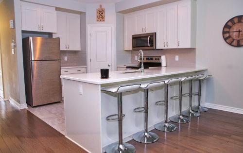 a kitchen with white cabinets and a counter with bar stools at Beautiful Nest By The Airport in Ottawa