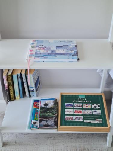 a white shelf with books and pamphlets in a refrigerator at Sirens Sunset Peaceful Retreat with stunning sea views, 5 minutes from Porth Beach in Newquay