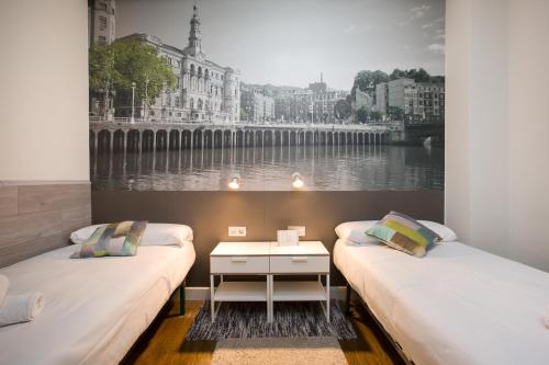 two beds in a room with a picture on the wall at Volantin Apartment in Bilbao