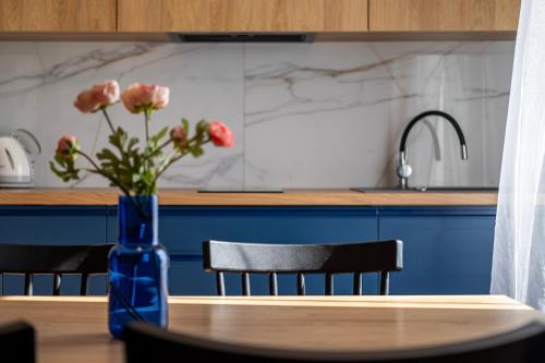 a blue vase with flowers on a table in a kitchen at 4 Pory Roku Apartamenty Domki Pokoje in Nadole