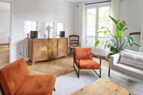 salon z pomarańczowymi krzesłami i kanapą w obiekcie Wonderful flat in Paris - Welkeys w Paryżu