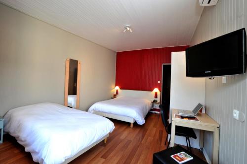 a hotel room with two beds and a flat screen tv at The Originals Access, Hôtel Arum, Remiremont in Remiremont