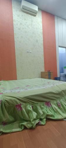 uma cama com um edredão verde num quarto em House of Nadifsa em Wendit