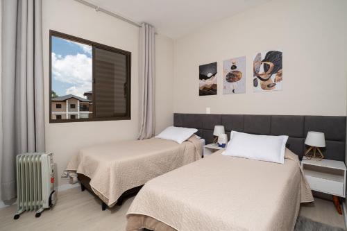 a room with two beds and a window at Alto da Montanha VIP Campos in Campos do Jordão