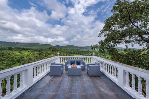 a balcony with chairs and a view of the mountains at SaffronStays Ivory Mansion in Pen