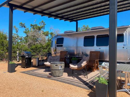 an rv parked under a pergola with chairs and a table at Airstream Alfresco in Fredericksburg