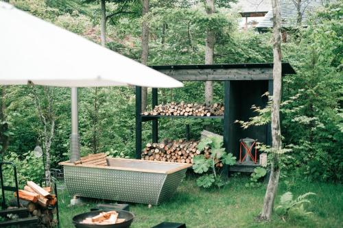 a hot tub in the yard with a bunch of wood at Karuizawa Forest Seasons Villa in Karuizawa