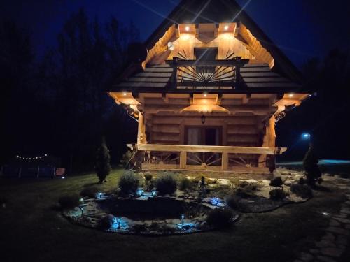 una cabaña de madera con un estanque delante de ella por la noche en Domek Jurgów 406, en Jurgów