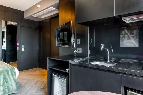een zwarte keuken met een wastafel en een tv bij Housi Bela Cintra in Sao Paulo