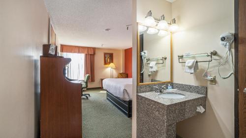 a hotel room with a bathroom with a bed and a sink at Days Inn & Suites by Wyndham Mt Pleasant in Mount Pleasant