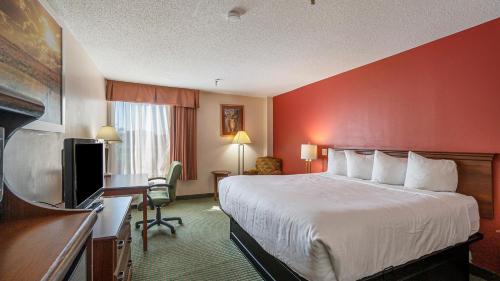 Days Inn & Suites by Wyndham Mt Pleasant في ماونت بليزنت: غرفة فندقية بسرير وتلفزيون بشاشة مسطحة