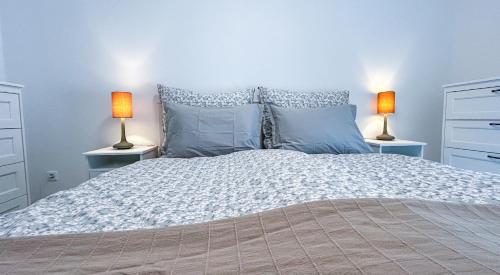 a bedroom with a large bed with two lamps on tables at Komfort Home Bursport Bt. ház in Balatonfenyves