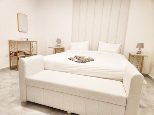 a bedroom with a large white bed with a chair at Moods Holiday Homes in Al Ain