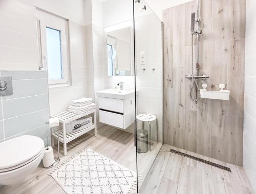 a white bathroom with a shower and a toilet at Komfort Home Bursport Bt. ház in Balatonfenyves